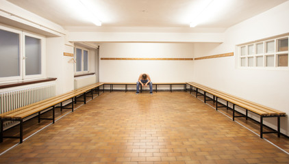 man sitting in empty locker room