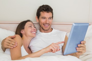 Fototapeta premium Happy couple using digital tablet in bed