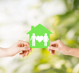 hands holding green house with family