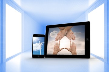 Composite image of hands and wind turbine on smartphone and tabl