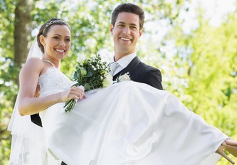 Groom carrying bride in garden