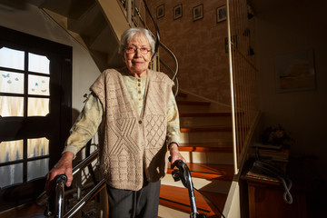 Fototapeta na wymiar Elderly woman with walking frame in the staircase