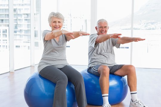 Senior Couple Doing Stretching Exercises On Fitness Balls