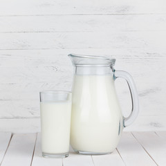 Milk glass and jar on white wooden table