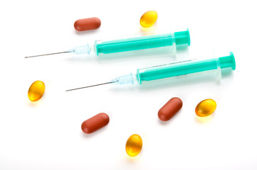 Syringes and pills over white