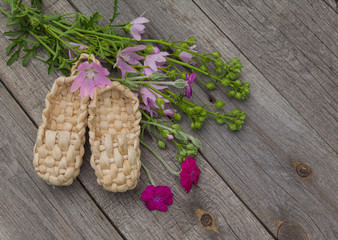 Rural still life with bast shoes and a bouquet of pink flowers