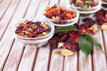 Aromatic dry tea in bowls on wooden background