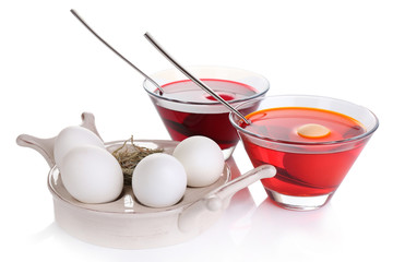 Eggs with liquid colour in glass bowls isolated on white
