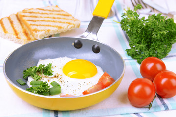 Scrambled eggs and bacon on frying pan on table close-up