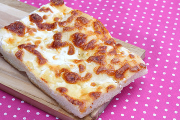 Focaccia with cheese on pink tablecloth