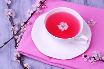 Fragrant tea with flowering branches on wooden table close-up
