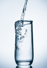 water pouring into glass on blue background