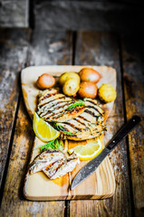 Grilled chicken with potatoes and herbs on wooden background