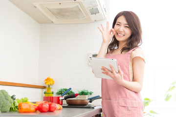 タブレットを見ながら料理をする女性