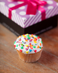 Cream cake with gifts on a wooden table.