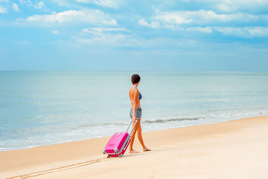 Woman with a suitcase on the beach
