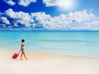 Fototapeta na wymiar Woman with a suitcase on the beach