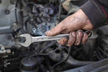 Car mechanic hold spanner tool in hand