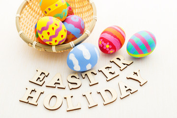 Colourful easter egg in basket with wooden text