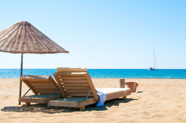 Sunbeds and rattan parasols on sandy seaside.