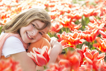 kleines Mädchen sitzt in einem Tulpenfeld