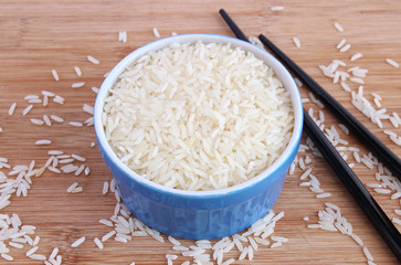 Uncooked jasmine rice in blue bowl with black chopsticks - 63451906