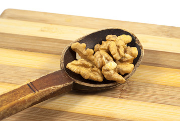 Walnut kernels into an old wooden spoon on a wooden board