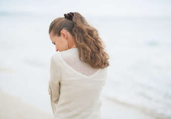 Fototapeta na wymiar Closeup on young woman walking on cold beach. rear view
