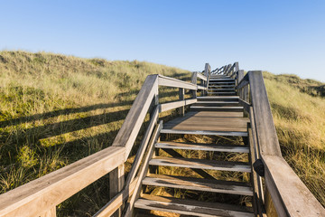 Wooden footpath through dunes at the North sea beach in Germany.