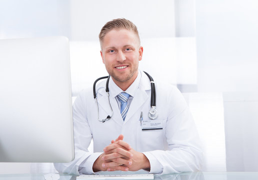 Smiling doctor or consultant sitting at a desk