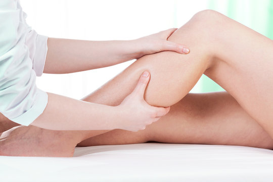 Hands massaging female leg