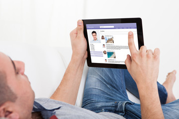 Man Chatting On Digital Tablet On Sofa