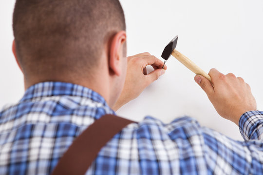 Hands Hammering Wall With Nail