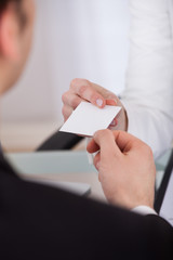 Businessman Giving Visiting Card To Colleague At Desk