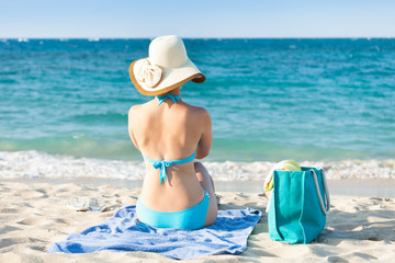Fototapeta na wymiar Woman in bikini relaxing on beach towel enjoying the ocean view