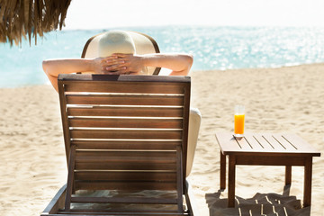 Woman relaxing on deck chair at beach resort