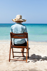Fototapeta na wymiar Woman sitting on chair at beach against sky
