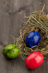 Easter eggs in hay nest on dark wood