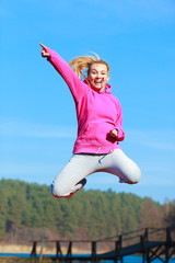 Cheerful woman teenage girl in tracksuit jumping showing outdoor