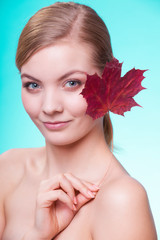 Naklejka na ściany i meble Skin care. Portrait of young woman girl with red maple leaf.