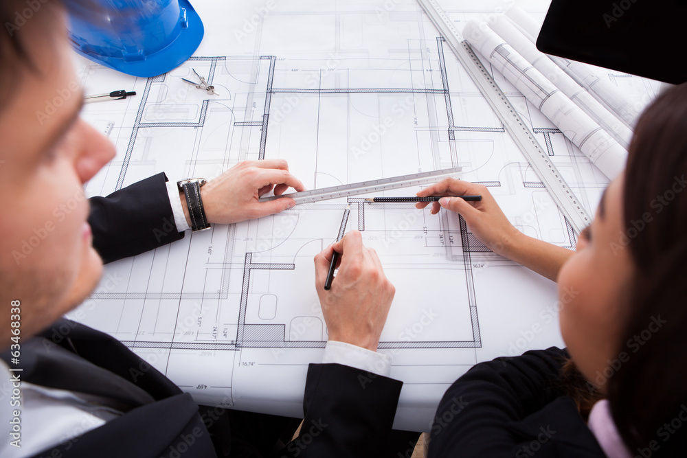 Poster architects working on blueprint at desk