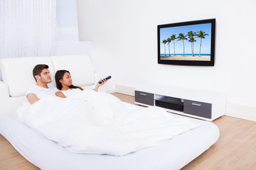 Couple Watching TV In Bed At Home