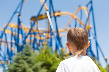 Boy next to a roller coaster