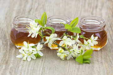 Obraz na płótnie Canvas Honey in jars and flowers on wooden background