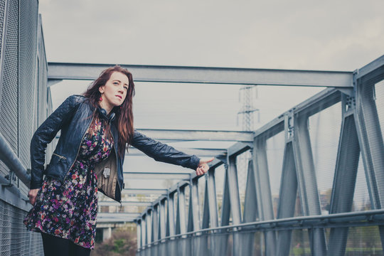 Pretty girl with long hair hitchhiking on a bridge