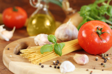 Pasta with tomatoes, olive oil and basil on wooden background