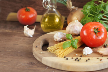 Pasta with tomatoes, olive oil and basil on wooden background