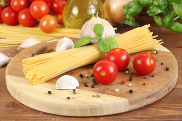Pasta with tomatoes, olive oil and basil on wooden background