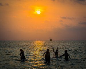 silhouetted group of boy are playing a ball in the sea