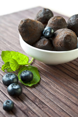 Chocolate truffles with blueberry and mint on wooden background